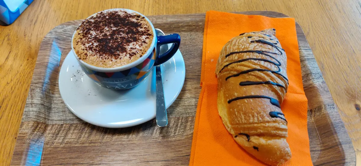 Foto de exemplo: Cappuccino e croissant com chocolate num tabuleiro
